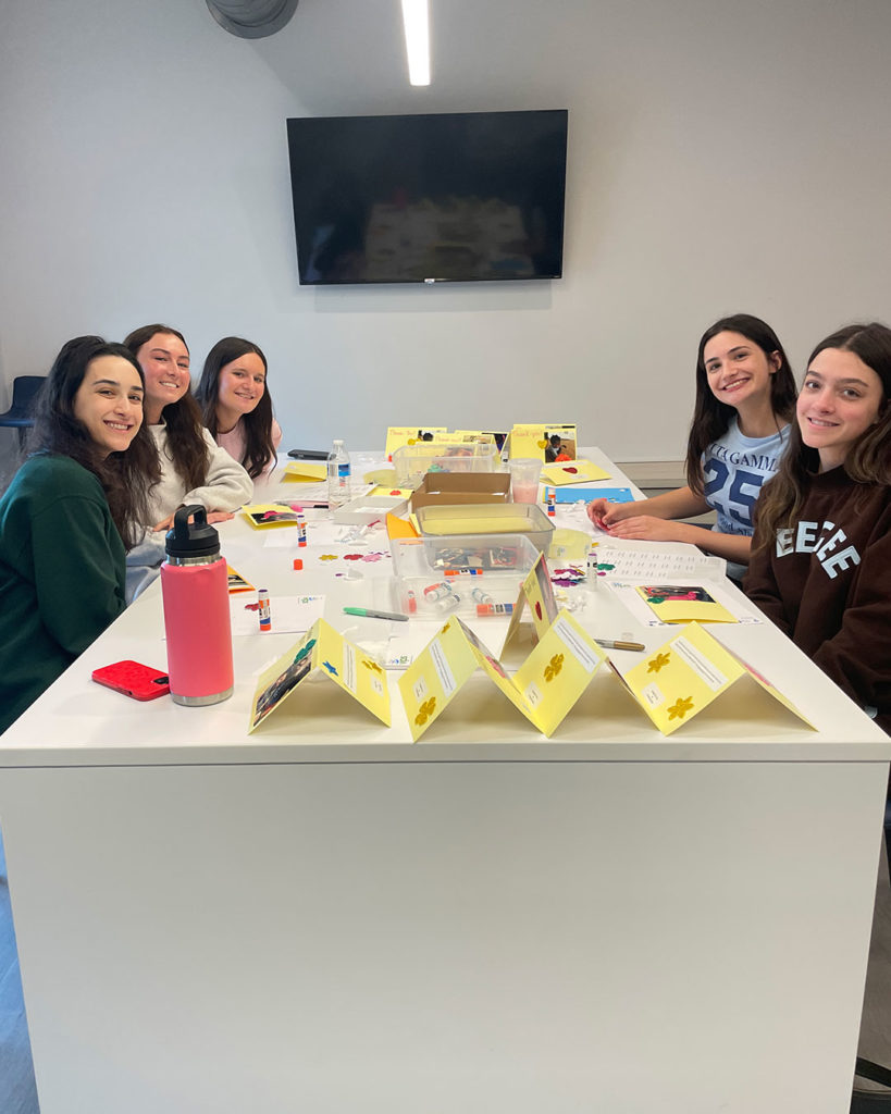 Five Delta Gammas hang out at the work table in the FRC and make cards.