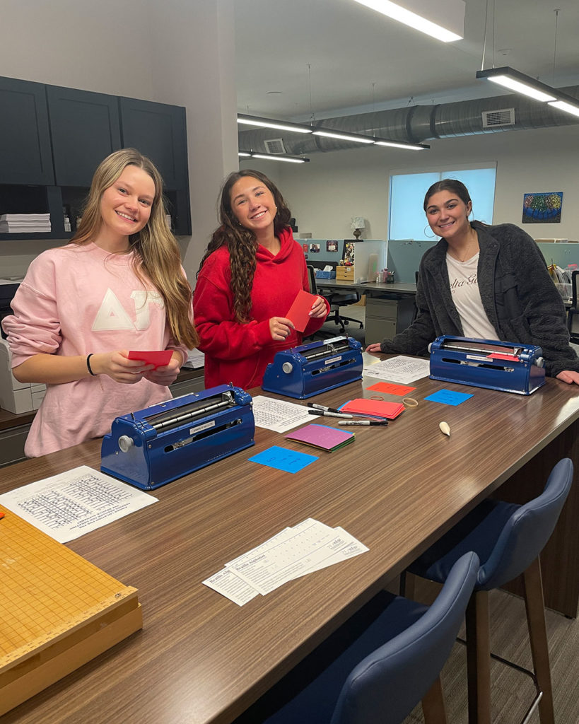 Three Delta Gammas make braille card inserts at the FRC.
