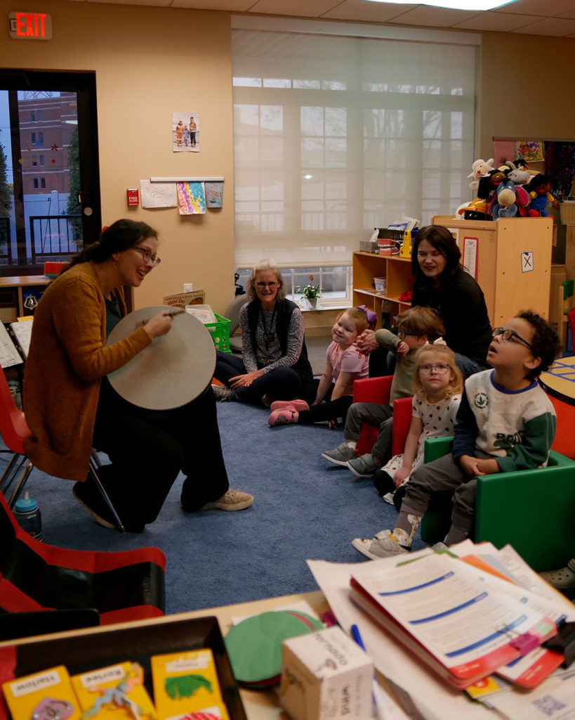 Jannell plays a drum for kids in the classroom.