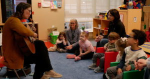 Jannell plays the guitar for kids in the classroom.