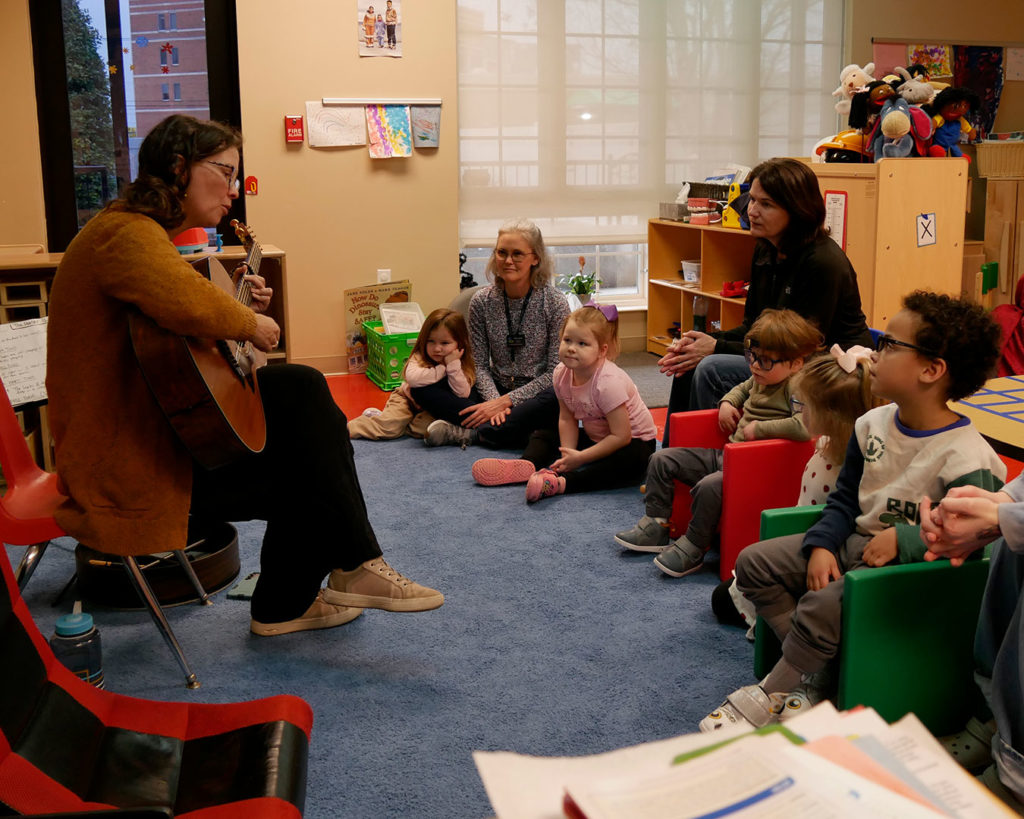 Jannell plays the guitar for kids in the classroom.