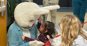 A small girl and a volunteer say hello to the Easter Bunny.