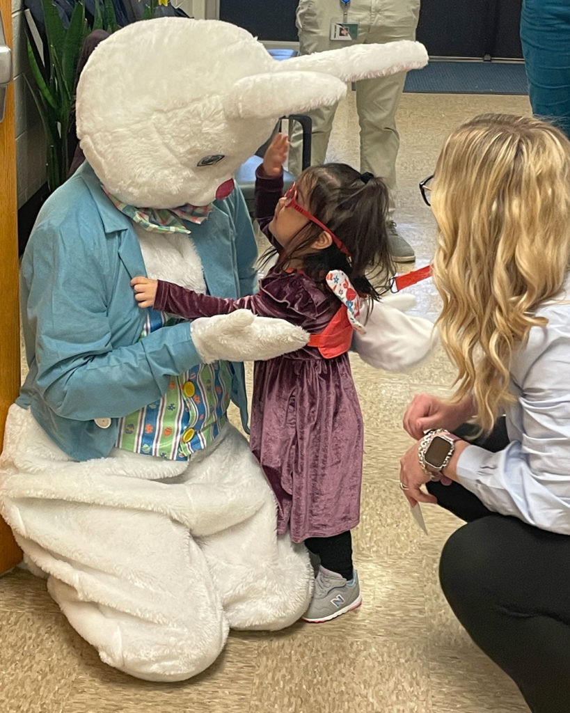A small girl and a volunteer say hello to the Easter Bunny.