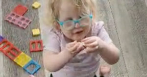 A small girl examines a puzzle piece.
