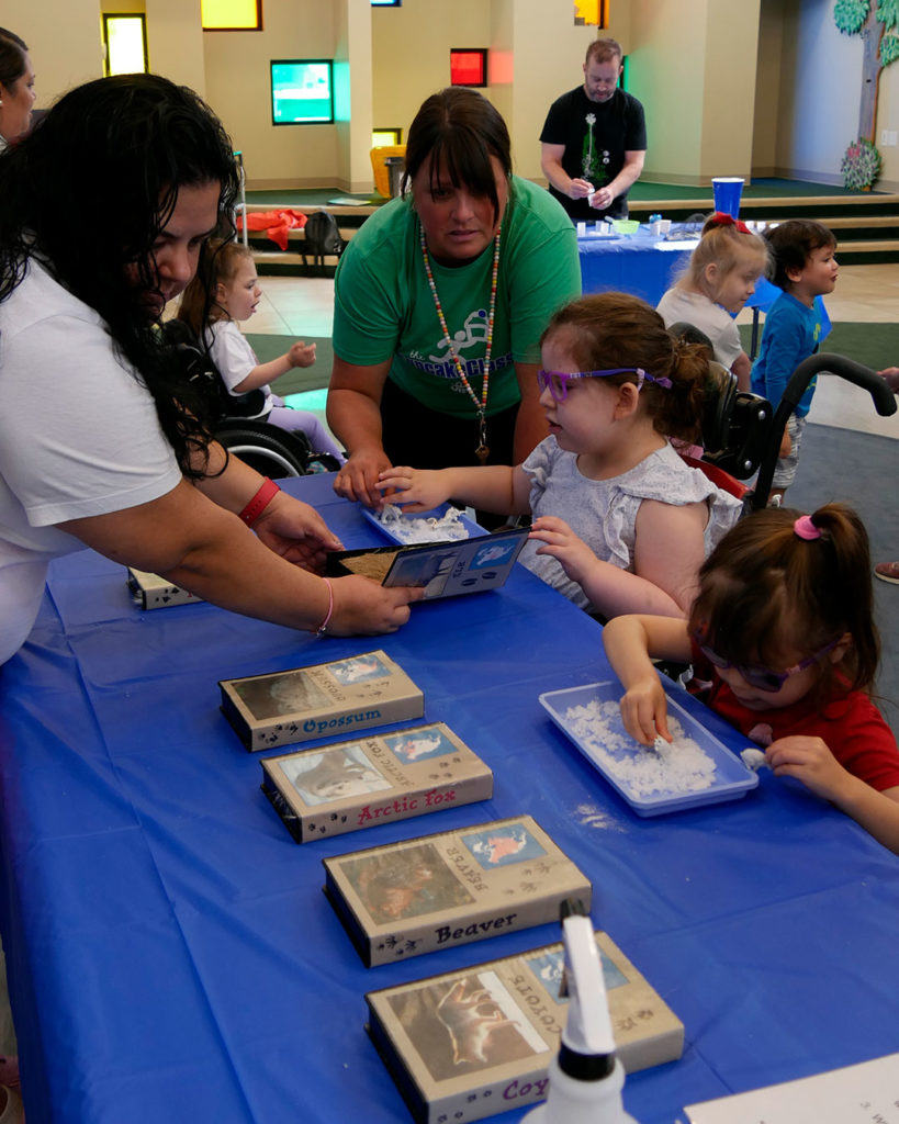 Two small girls play with trays of Insta Snow.