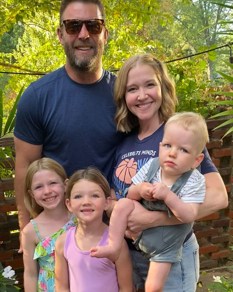 Wells and his family pose for a photo on a patio surrounded by plants and trees.