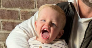 Wells is laughing while in the arms of his father.