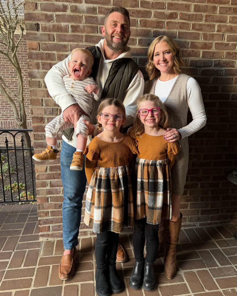 Wells and his family pose for a photo on a porch against a brick wall.
