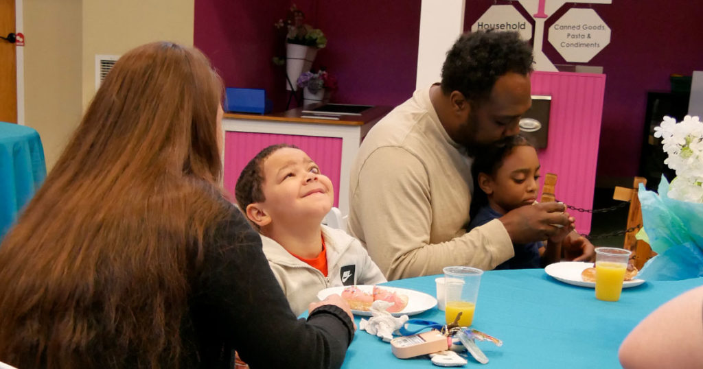Parents sit with their children while enjoying juice and donuts.
