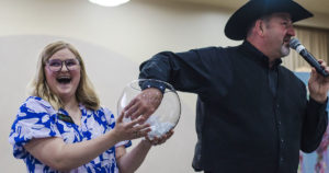 Auctioneer Shaun Logsdon pulls the Golden Ticket winning name from a fish bowl held by Justine Aycock.