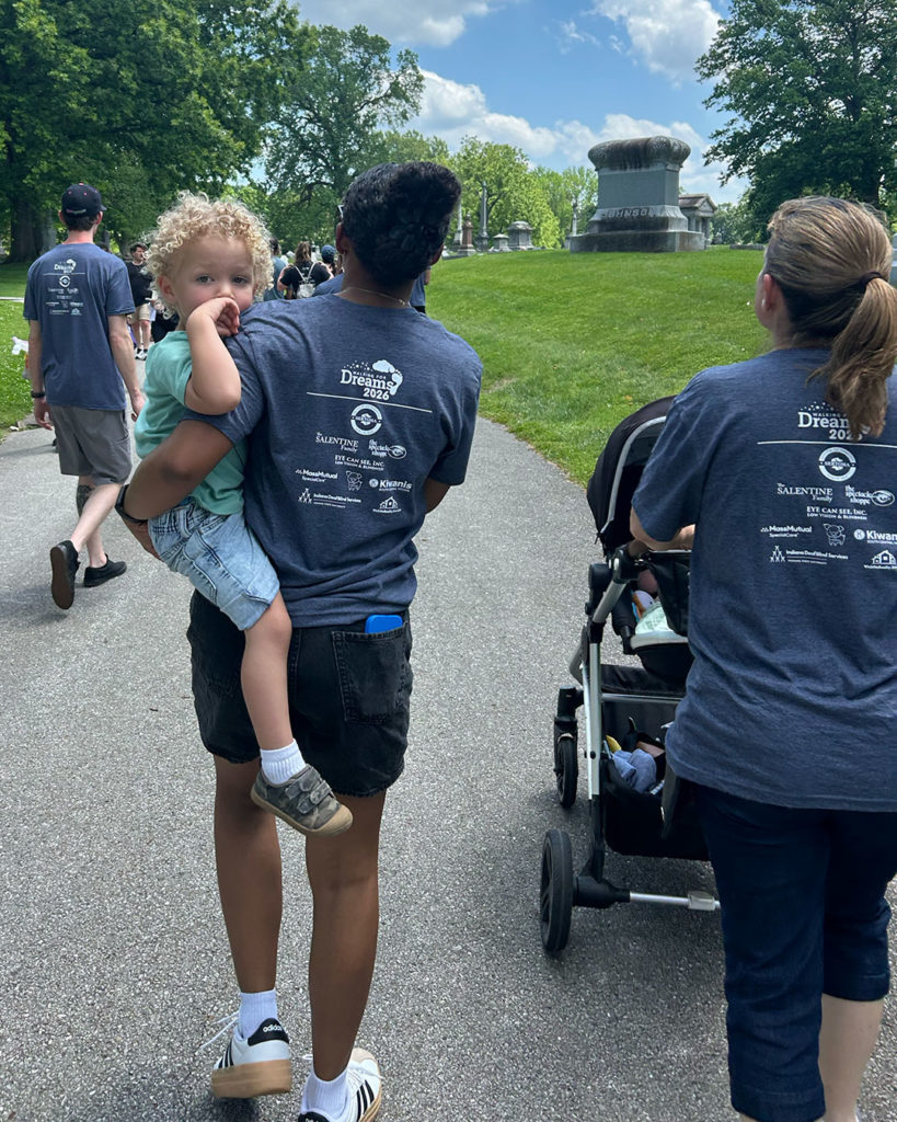 A mother carrying her daughter on her hip and another pushing a stroller during Walking for Dreams.