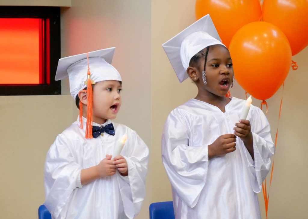 Graduates hold electric candles and sing "This Little Light of Mine."