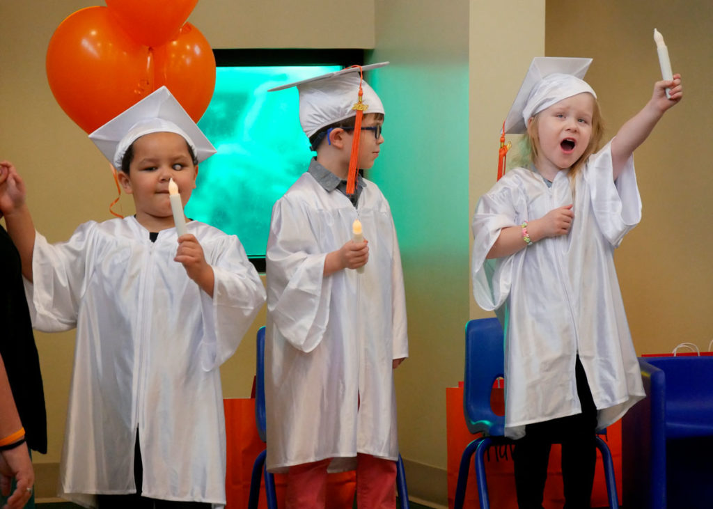 Graduates hold electric candles and sing "This Little Light of Mine."