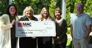 Diane Nelson, Justine Aycock, and MAC Construction staff members pose for a photo with a giant check for $29,100.