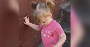 Emery is walking down concrete stairs, steadying herself with her hand on the wall.