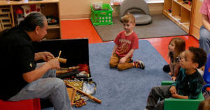 Fernando from Louisville Folk School demonstrates how to use instruments to the students.