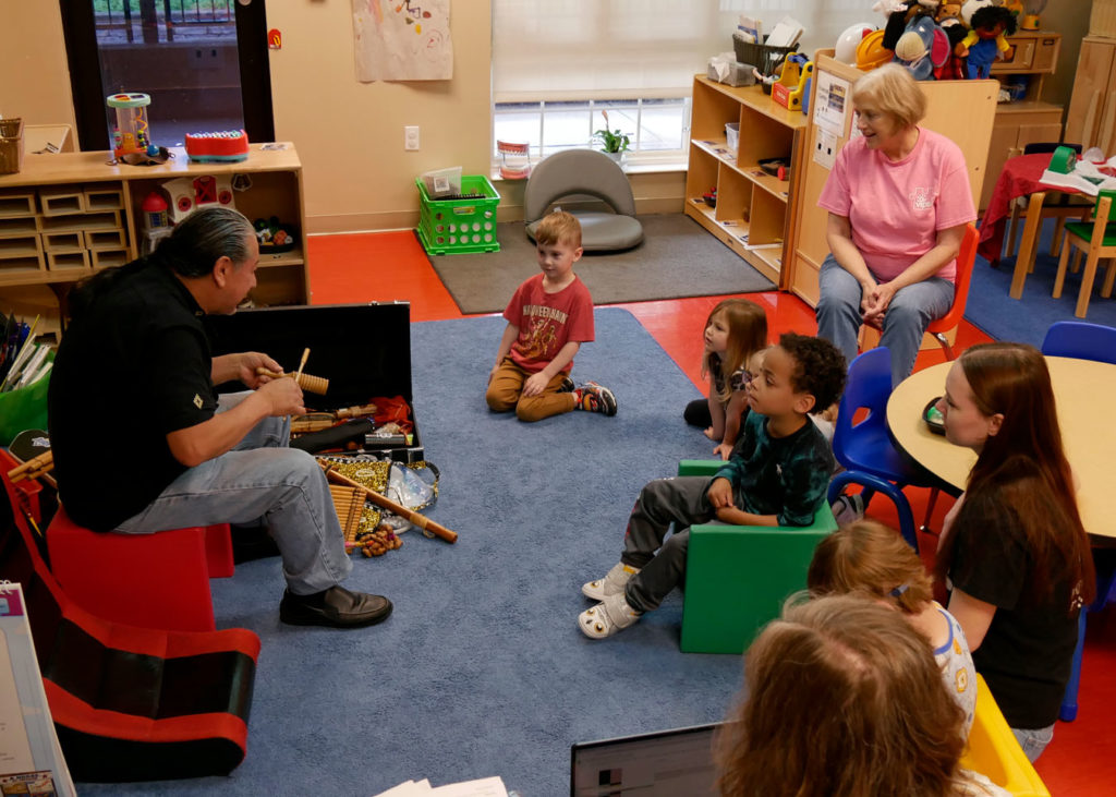 Fernando from Louisville Folk School demonstrates how to use instruments to the students.