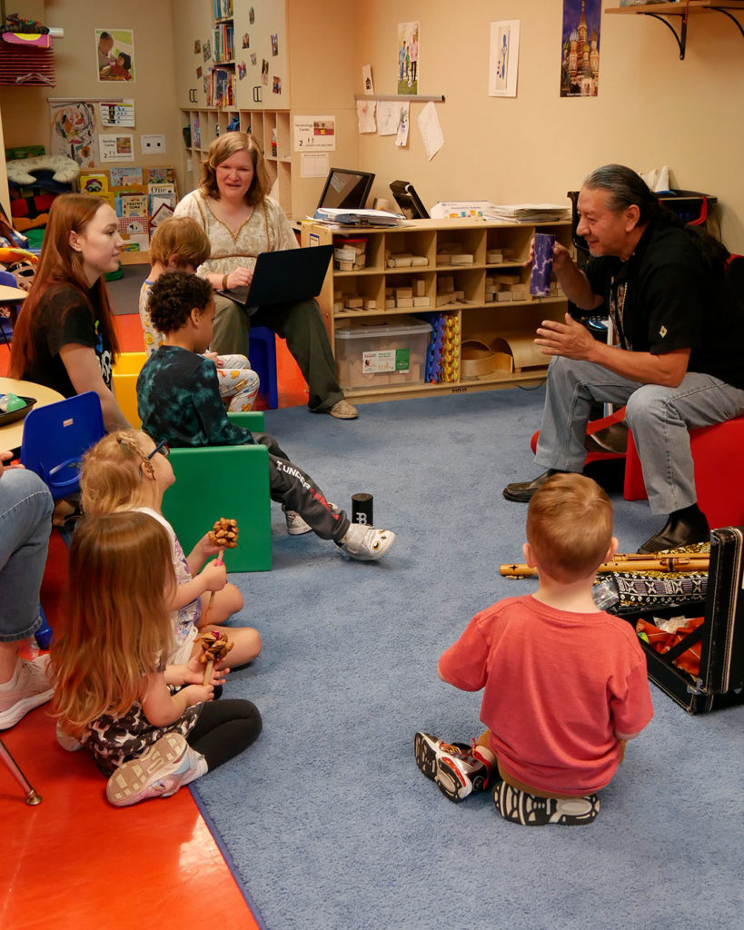 Fernando from Louisville Folk School demonstrates how to use instruments to the students.