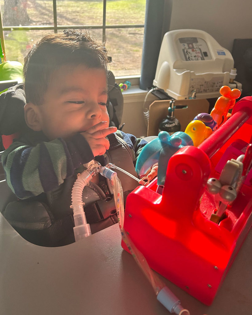 Angelito sits in a chair and plays with an interactive toy.