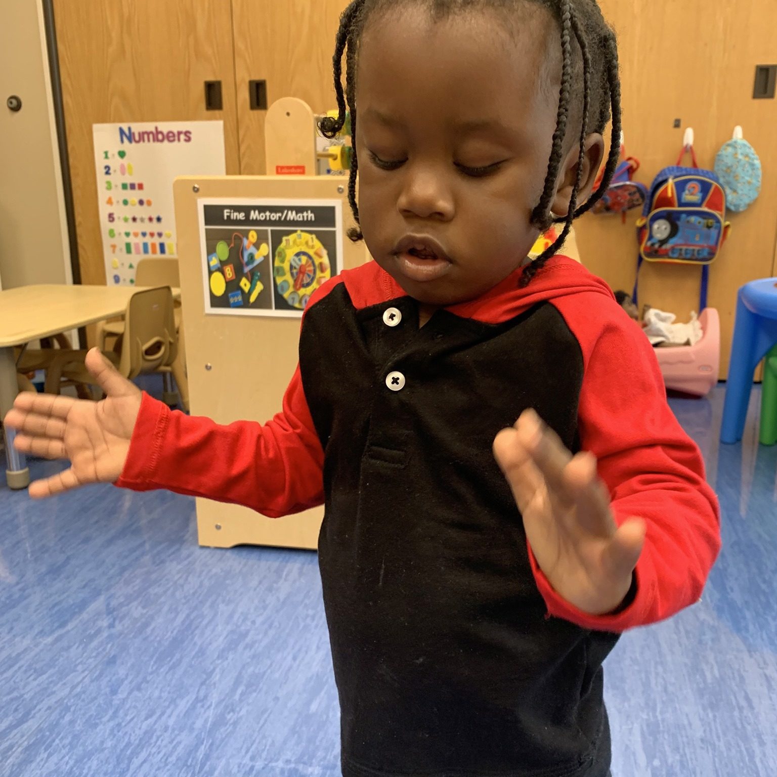 A little boy is standing while holding a toy.