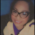 Woman with glasses smiling.