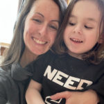 Woman with long dark hair has her arms wrapped around her son. Both are smiling.